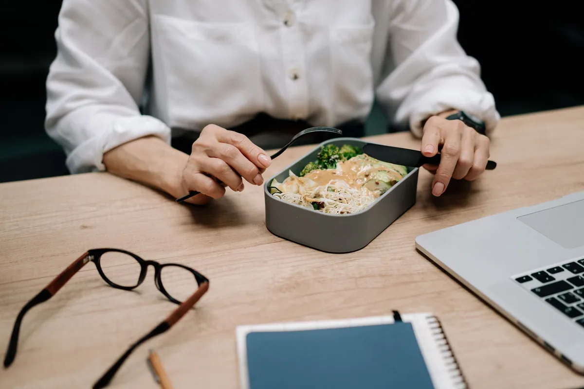 Person eating a healthy prepared meal at an office desk