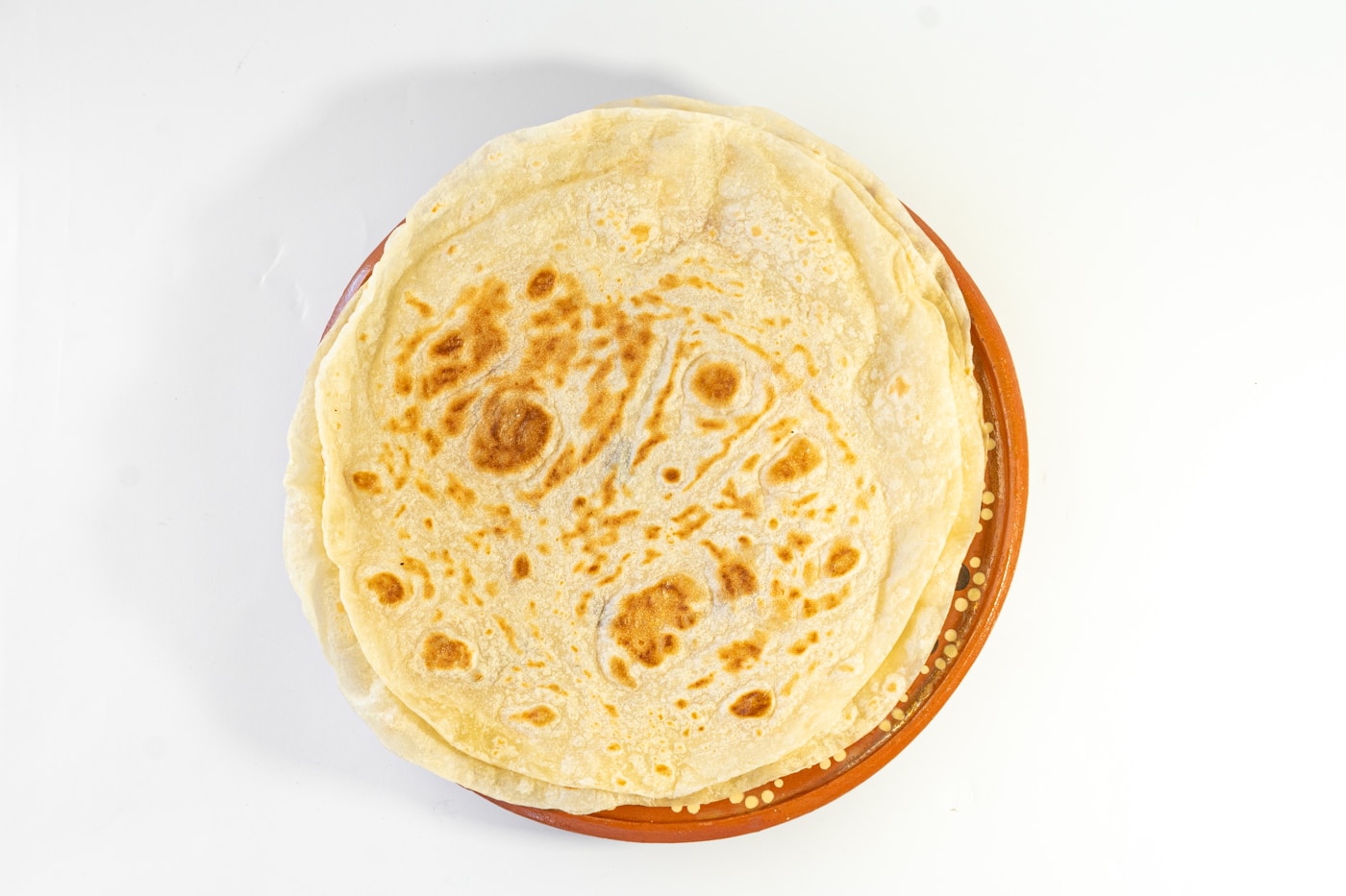 A stack of fresh flour tortillas on a plate