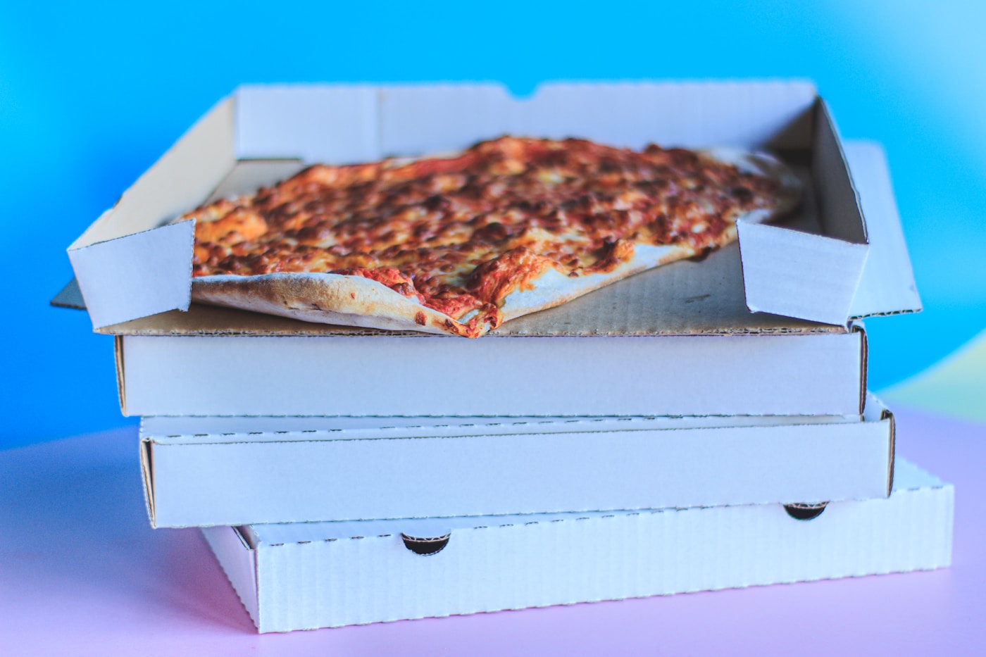 Multiple pizza boxes stacked, one open showing a whole pizza
