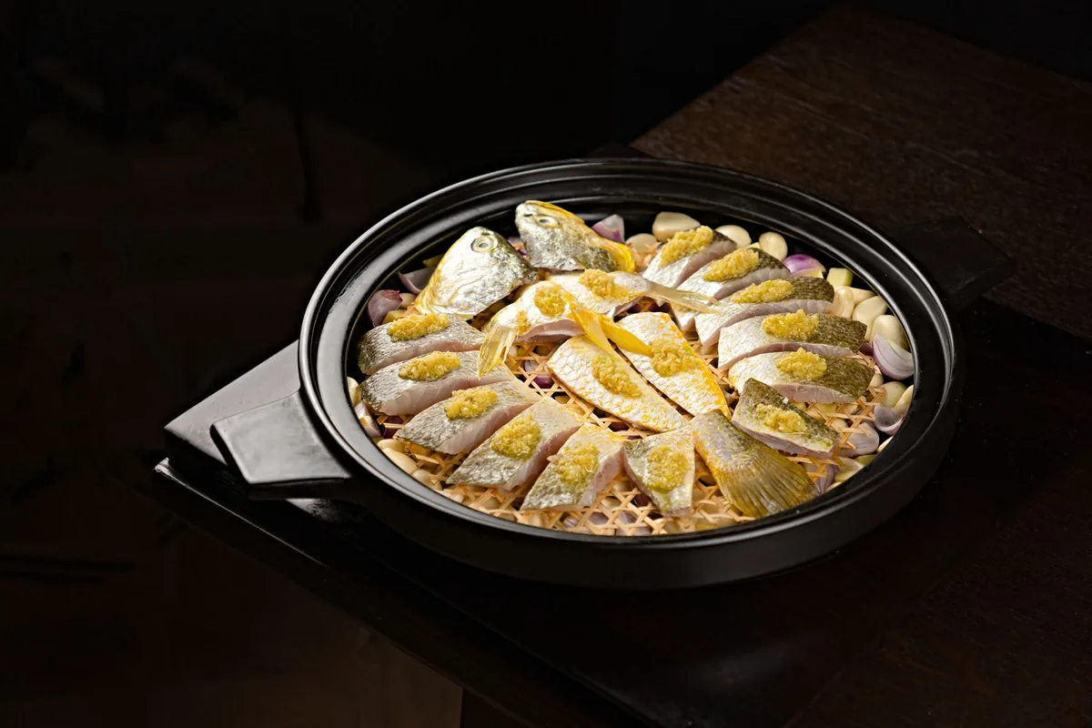 Steamed fish with garlic in a black steamer