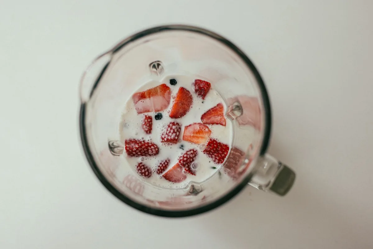 Strawberries and milk in a blender jug