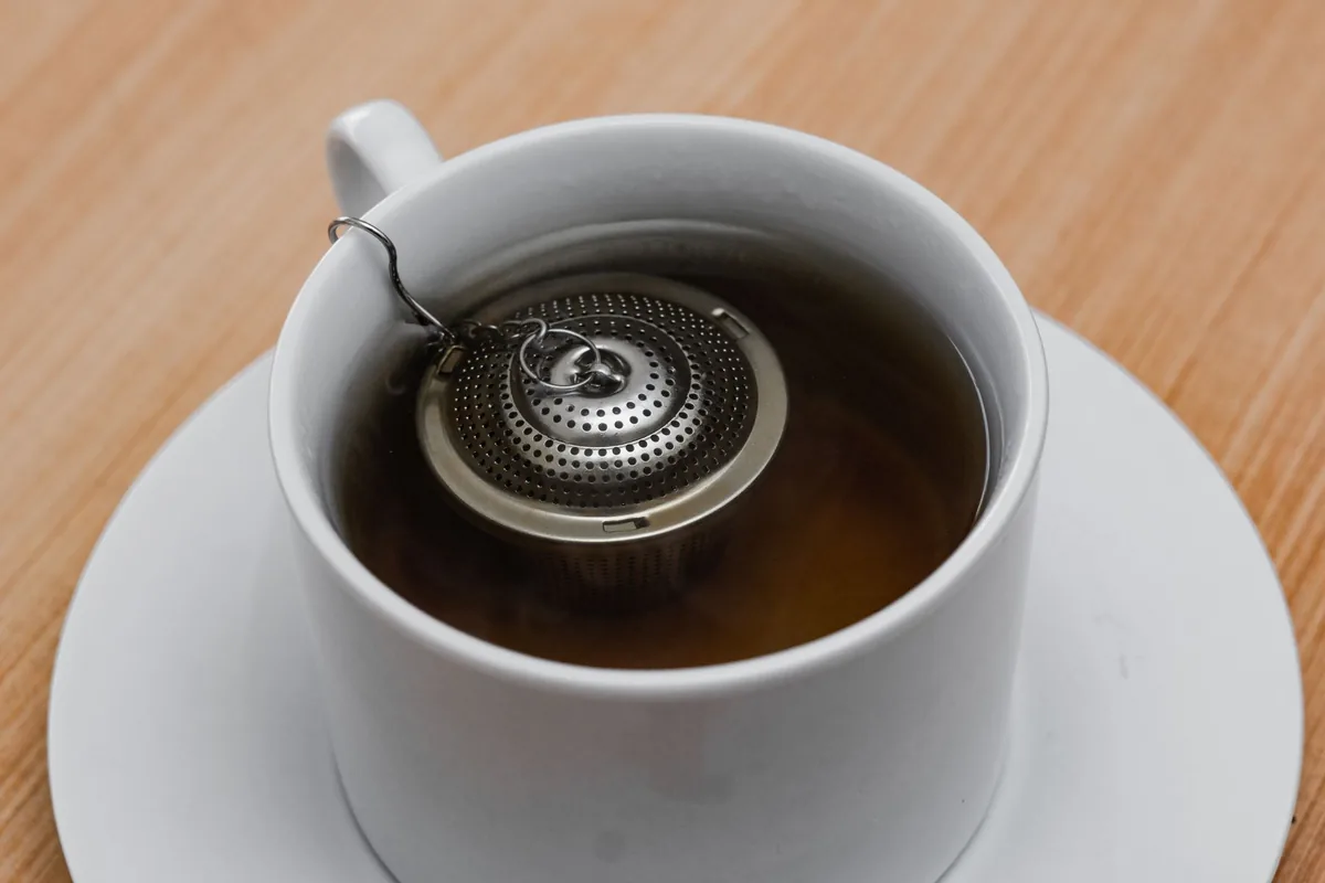 A tea infuser steeping in a white cup