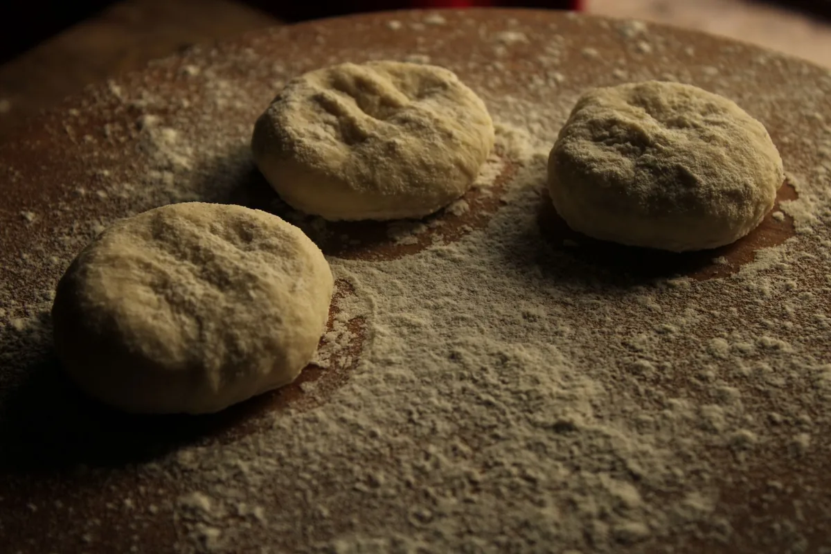 Three raw dough balls on a floured surface