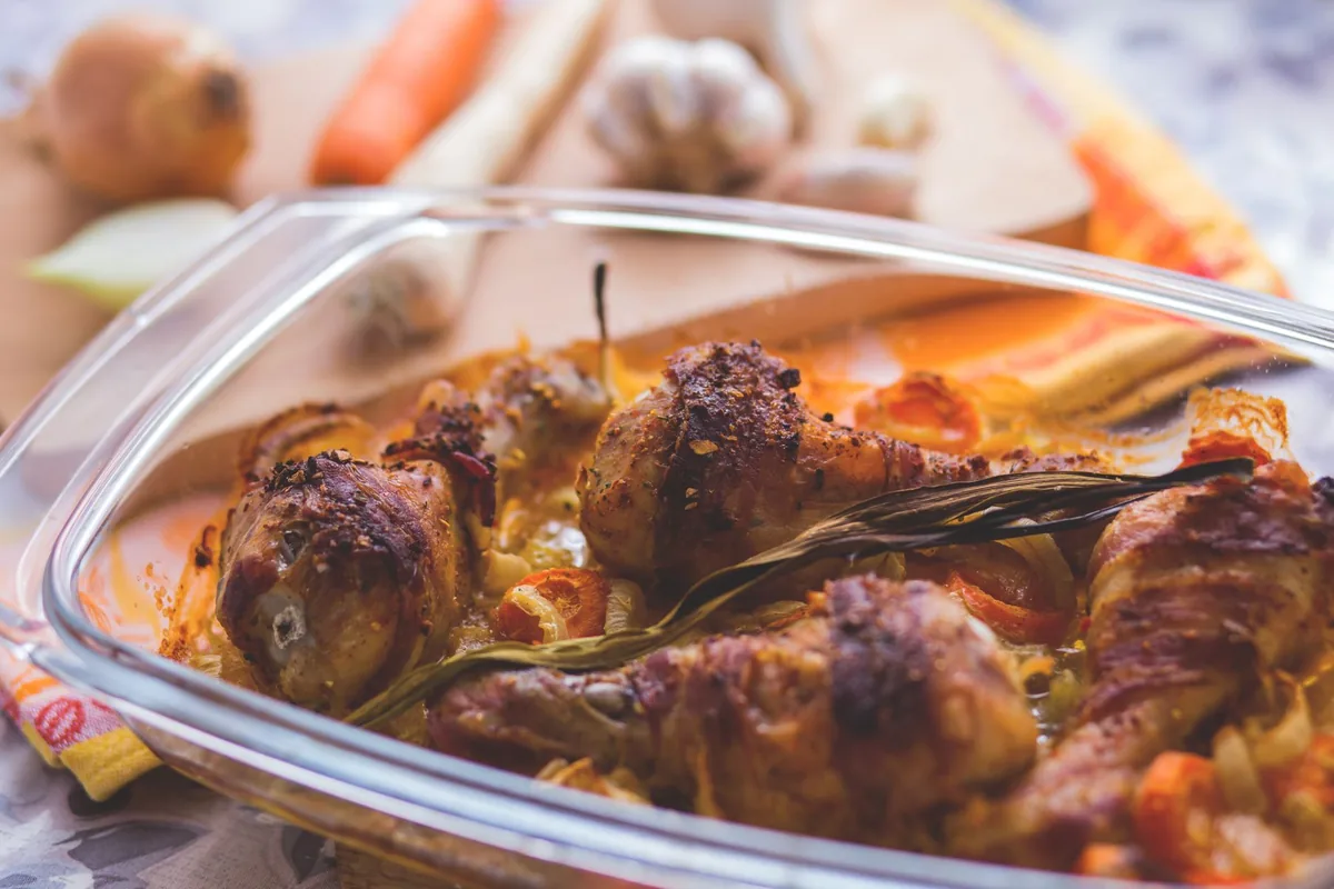 Roasted chicken drumsticks with vegetables in a tray