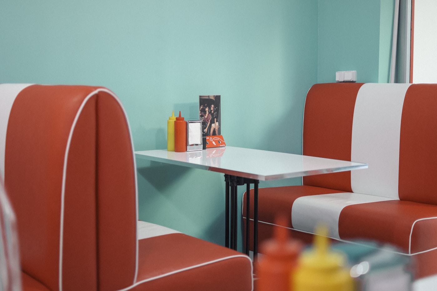 Retro 1960s diner booth interior with red vinyl seats, evoking the era Hawaiian pizza was invented