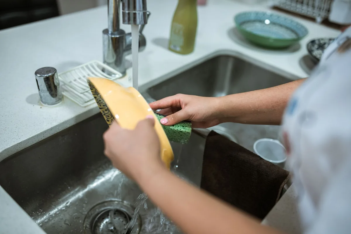 Person washing a metal filter under running water