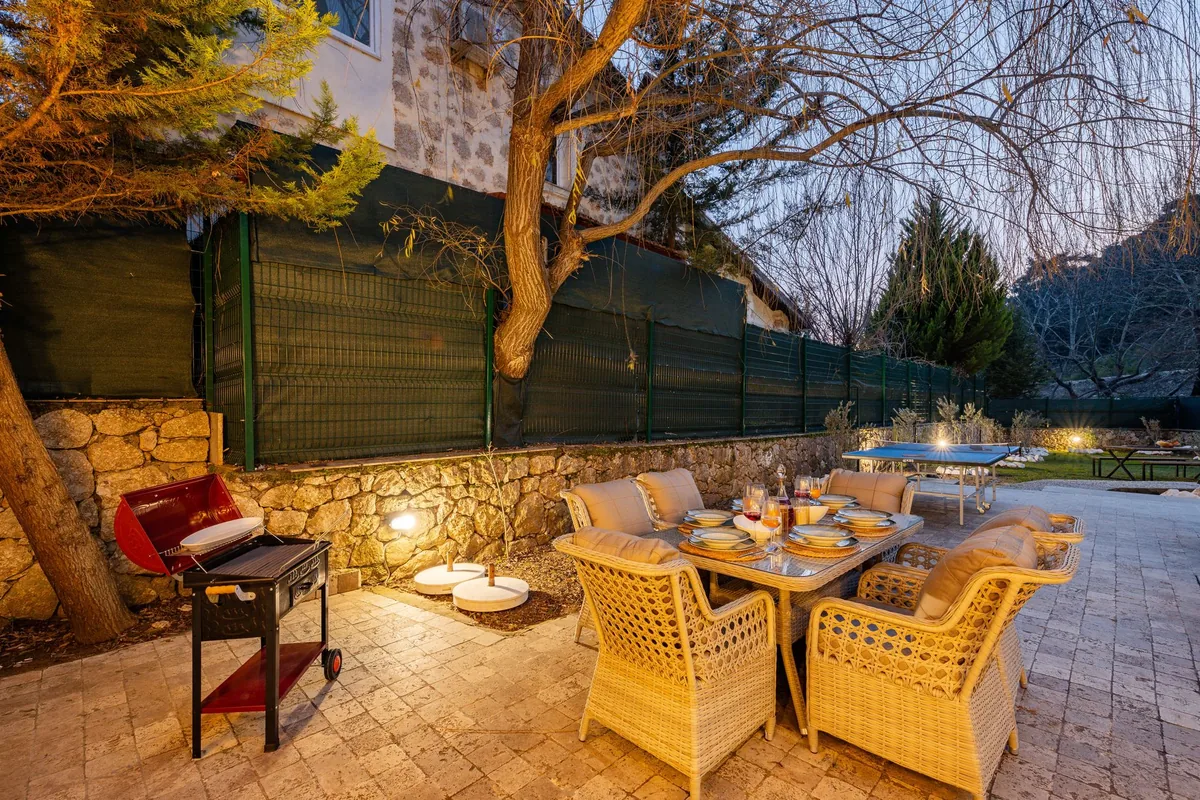 A backyard patio with a grill and seating at dusk