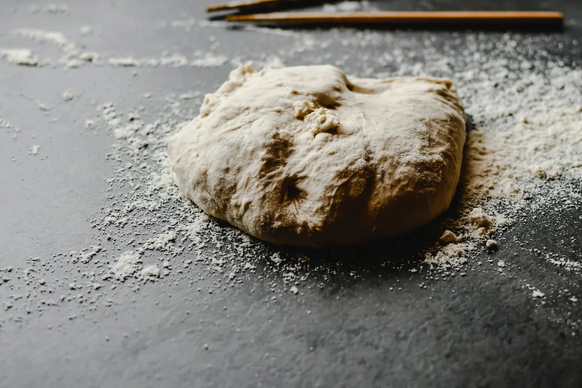 A ball of dough on a floured dark counter