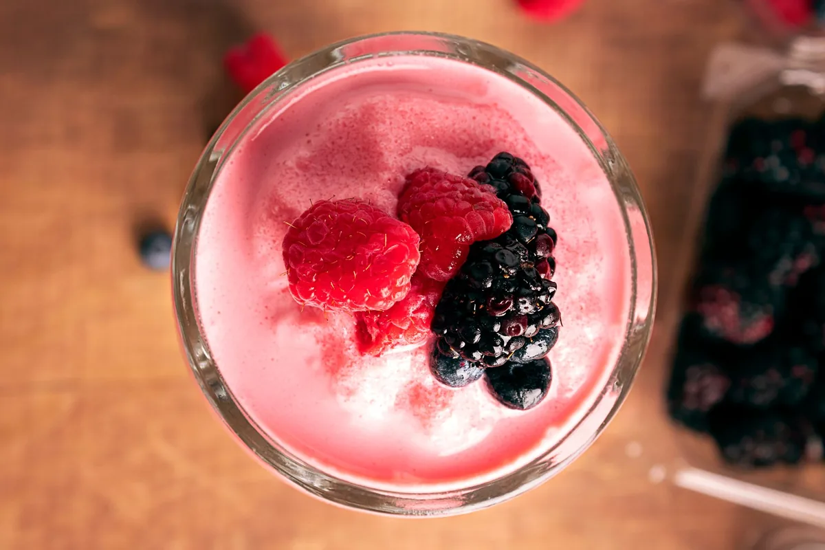A berry smoothie topped with raspberries and blackberries, seen from above