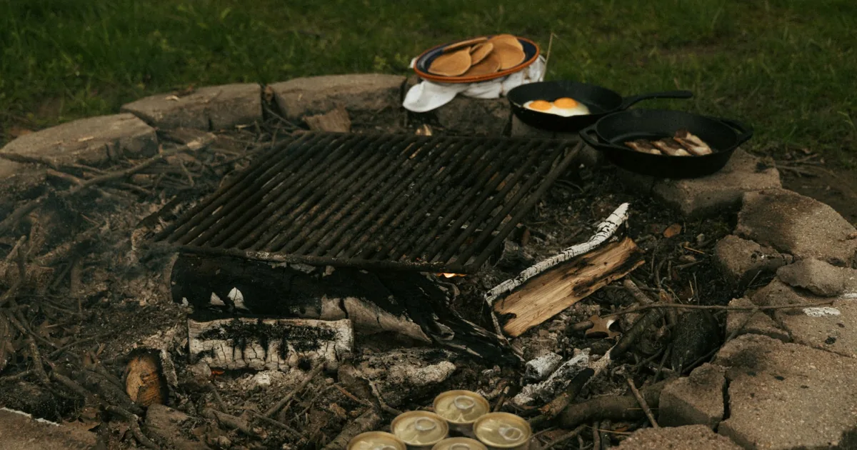 Cast iron pans on a grate over a stone fire pit