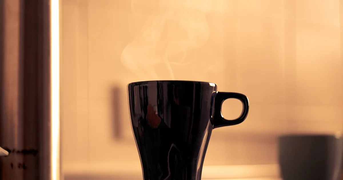 A black coffee mug on a kitchen counter in warm morning light