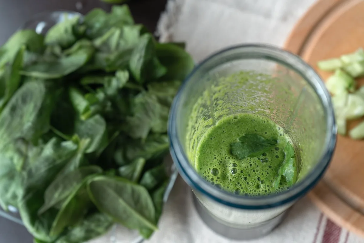 A blender jar filled with a bright green smoothie on a white counter