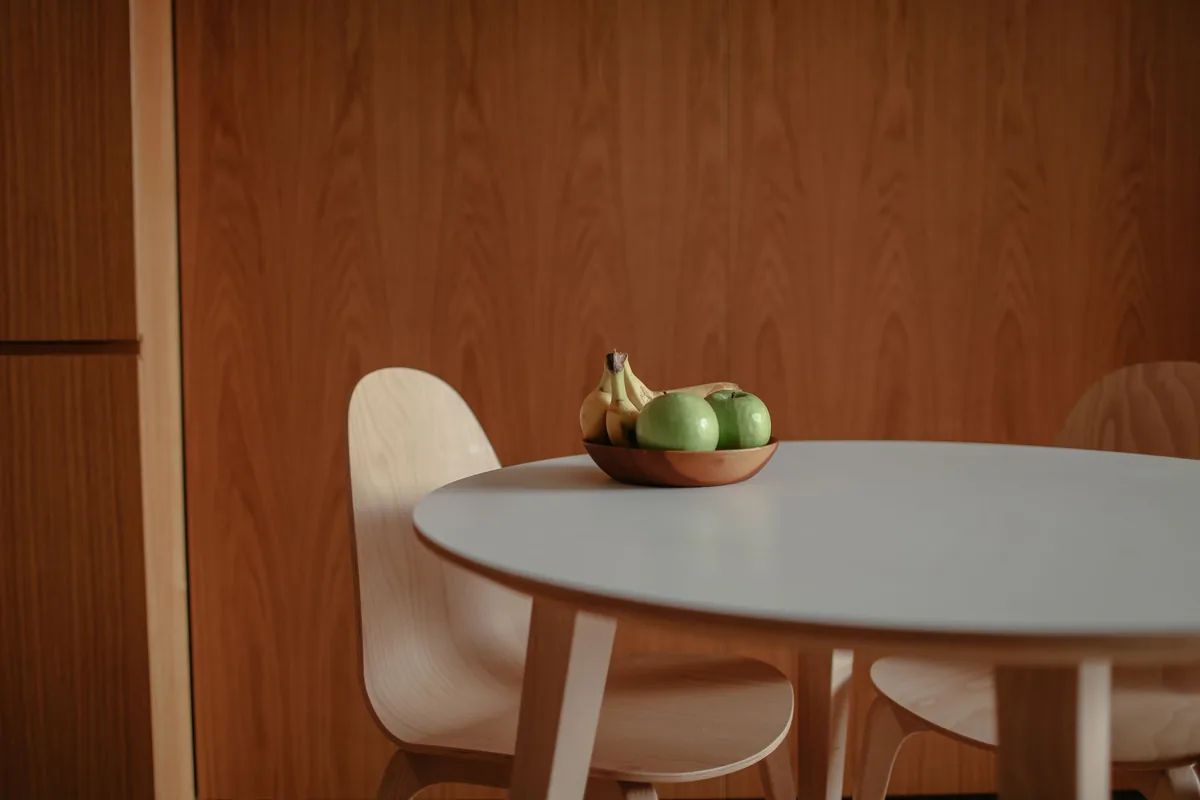 A bowl of red apples and yellow bananas on a bright kitchen table