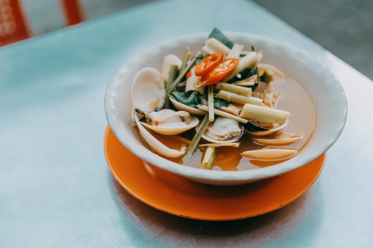 A bowl of soup with clams and vegetables