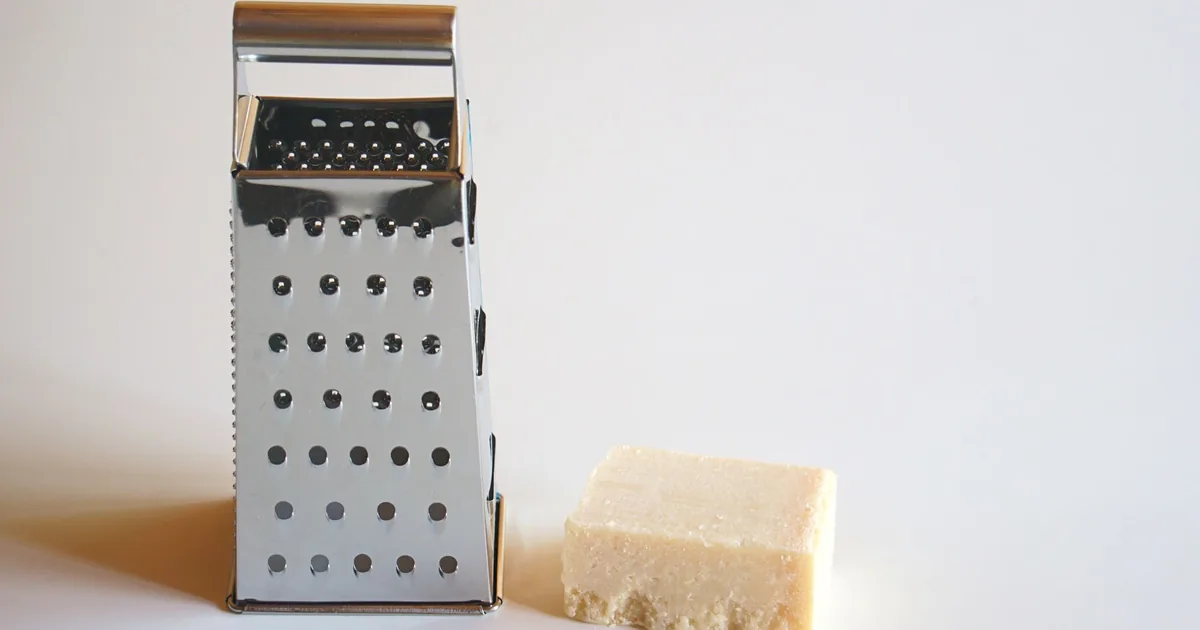 A box grater beside a block of cheese