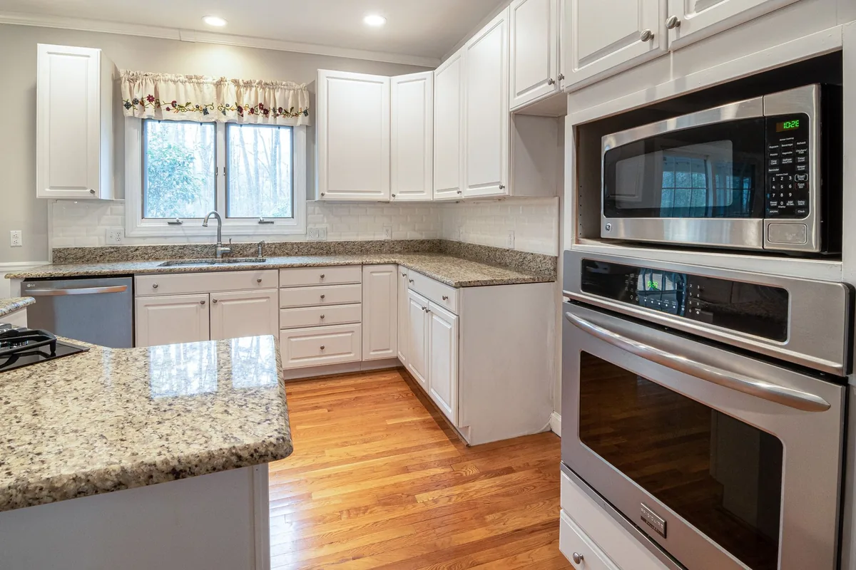 A bright kitchen with a wall oven and microwave above granite counters