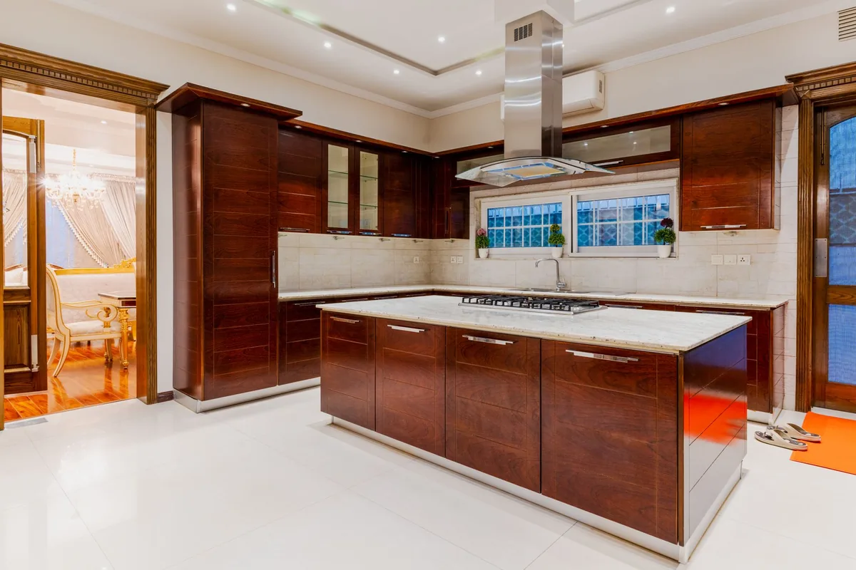 A wood-panelled kitchen with an island under a chimney hood