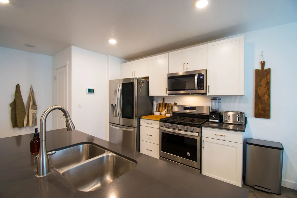 A white kitchen with a small stainless bin beside the counter