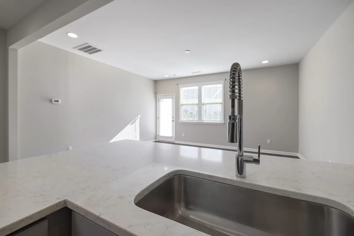 A brushed stainless steel sink basin with water droplets on its surface