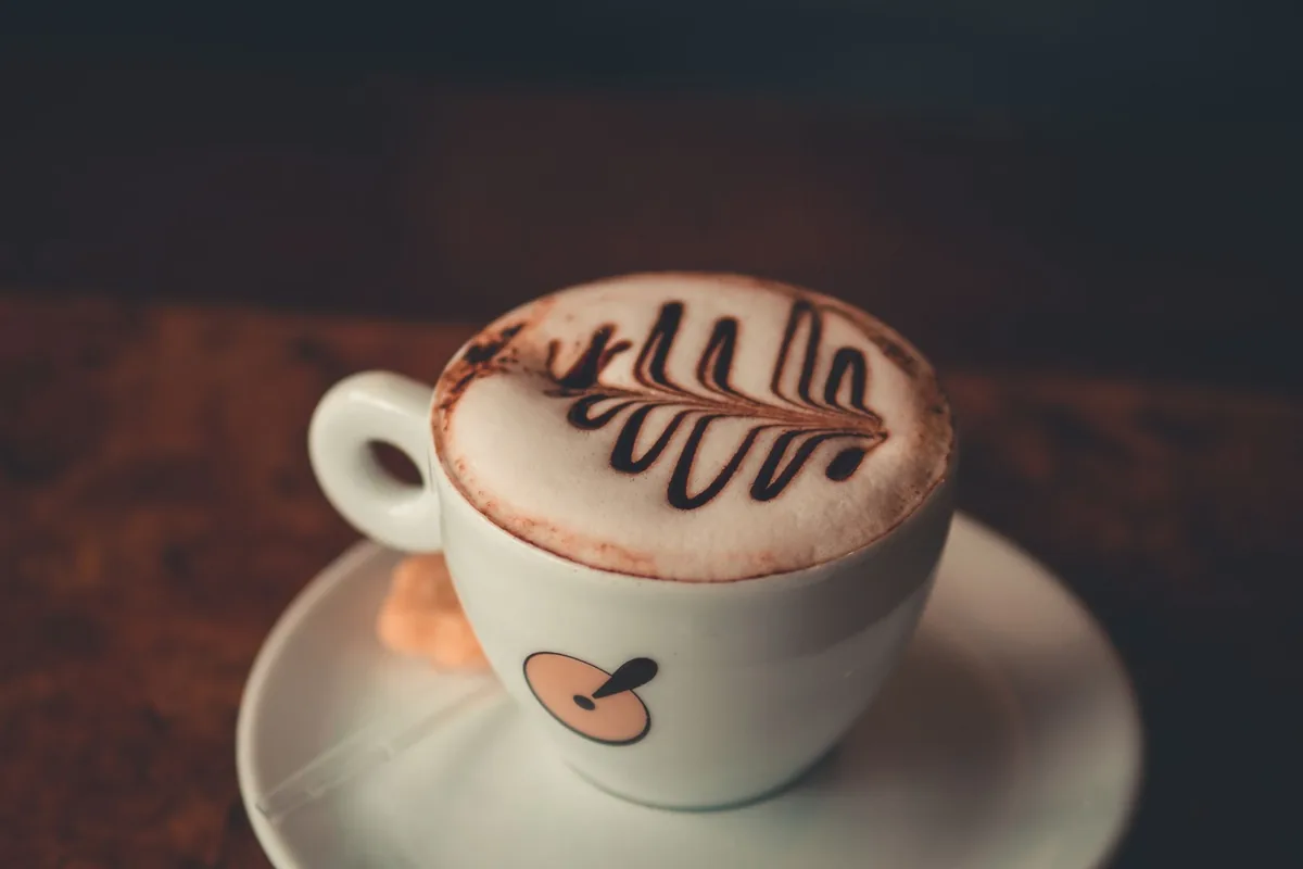 A cappuccino dusted with a cocoa leaf pattern
