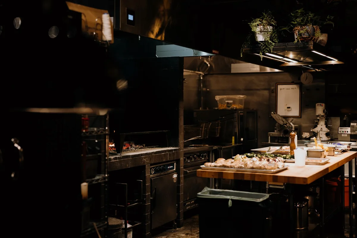 A clean commercial prep station with trays of chopped vegetables lined up on steel shelving