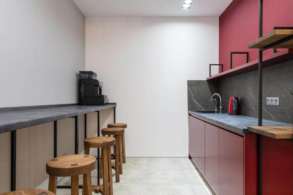 A clean office kitchen with a counter and stools