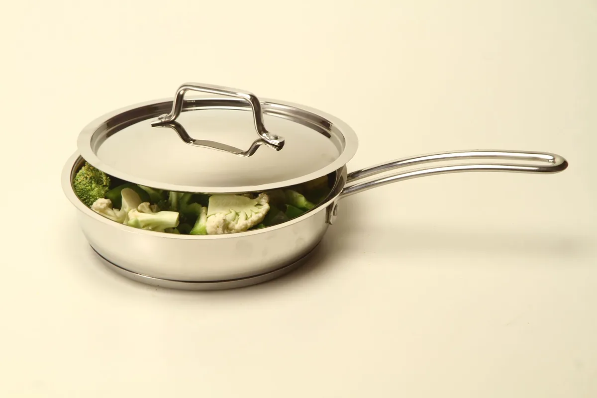 A stainless steel pan with a steel lid holding broccoli