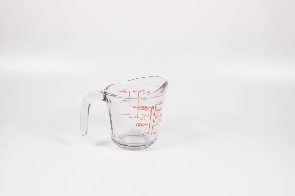 A clear measuring jug with marked volume lines on a kitchen surface