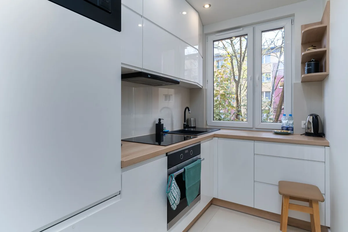 A compact apartment kitchen with a narrow range, white cabinets and a short run of counter
