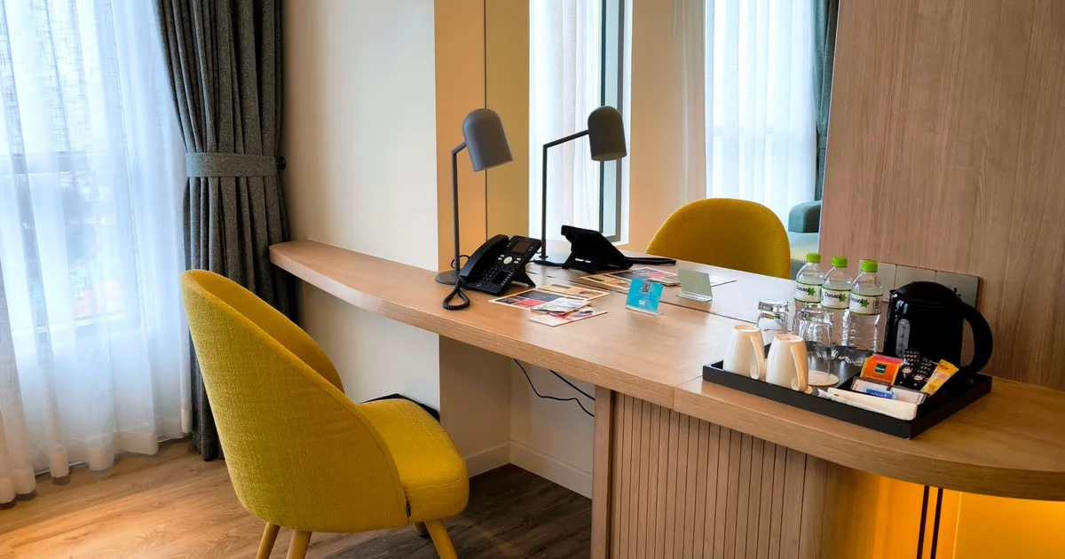 A hotel room desk with a kettle and drinks tray