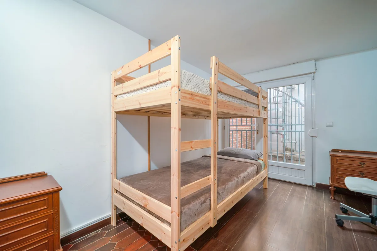 A small room with a wooden bunk bed and a desk