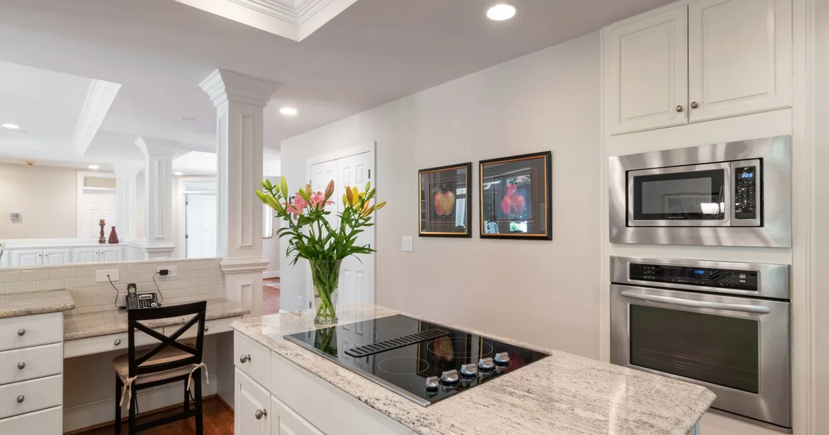 A bright kitchen with a built-in microwave above a wall oven