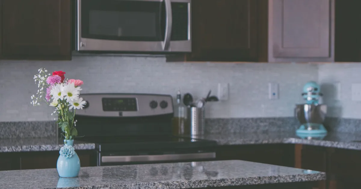 A kitchen with a microwave mounted above the cooker and granite worktops