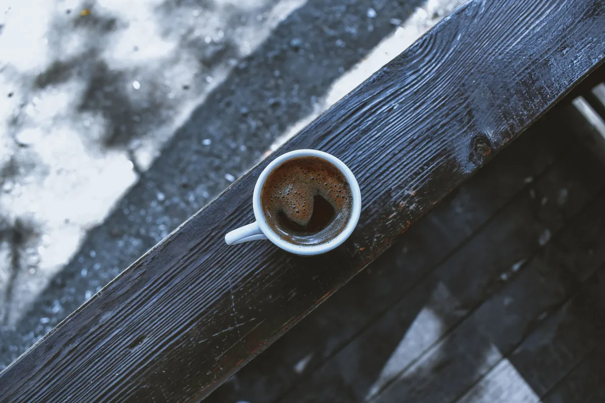 A cup of black coffee on a wooden table in morning light