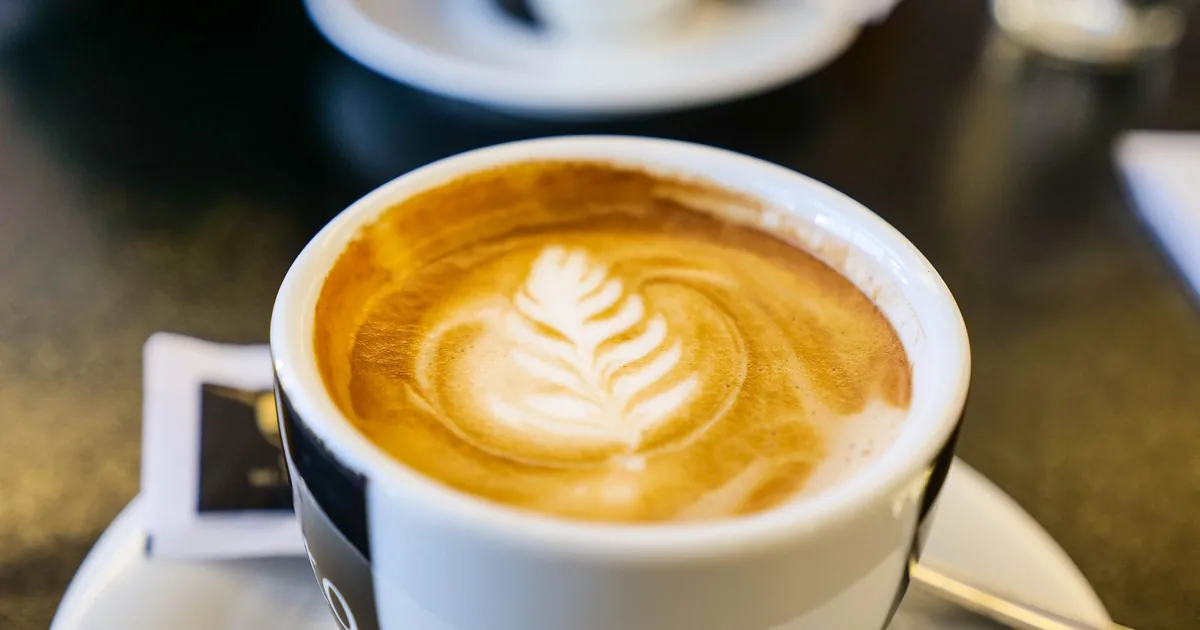 A cup of latte with leaf-pattern foam