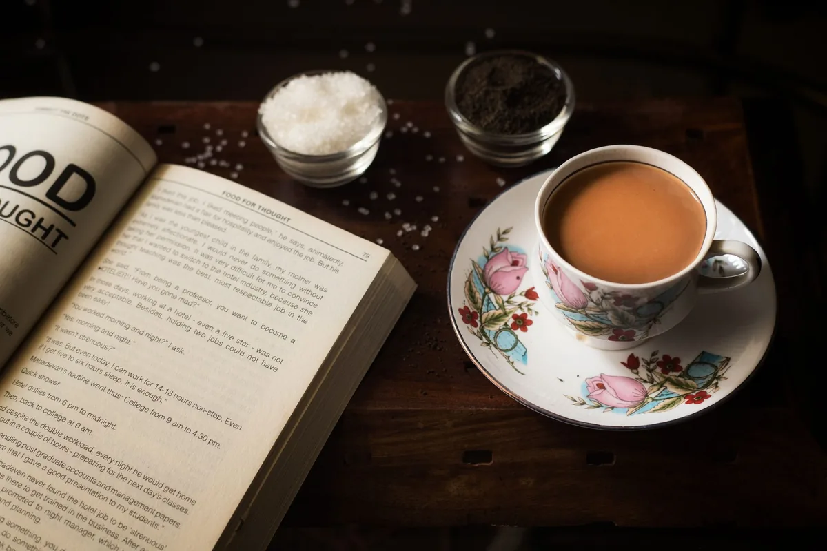 A cup of milky tea beside an open book