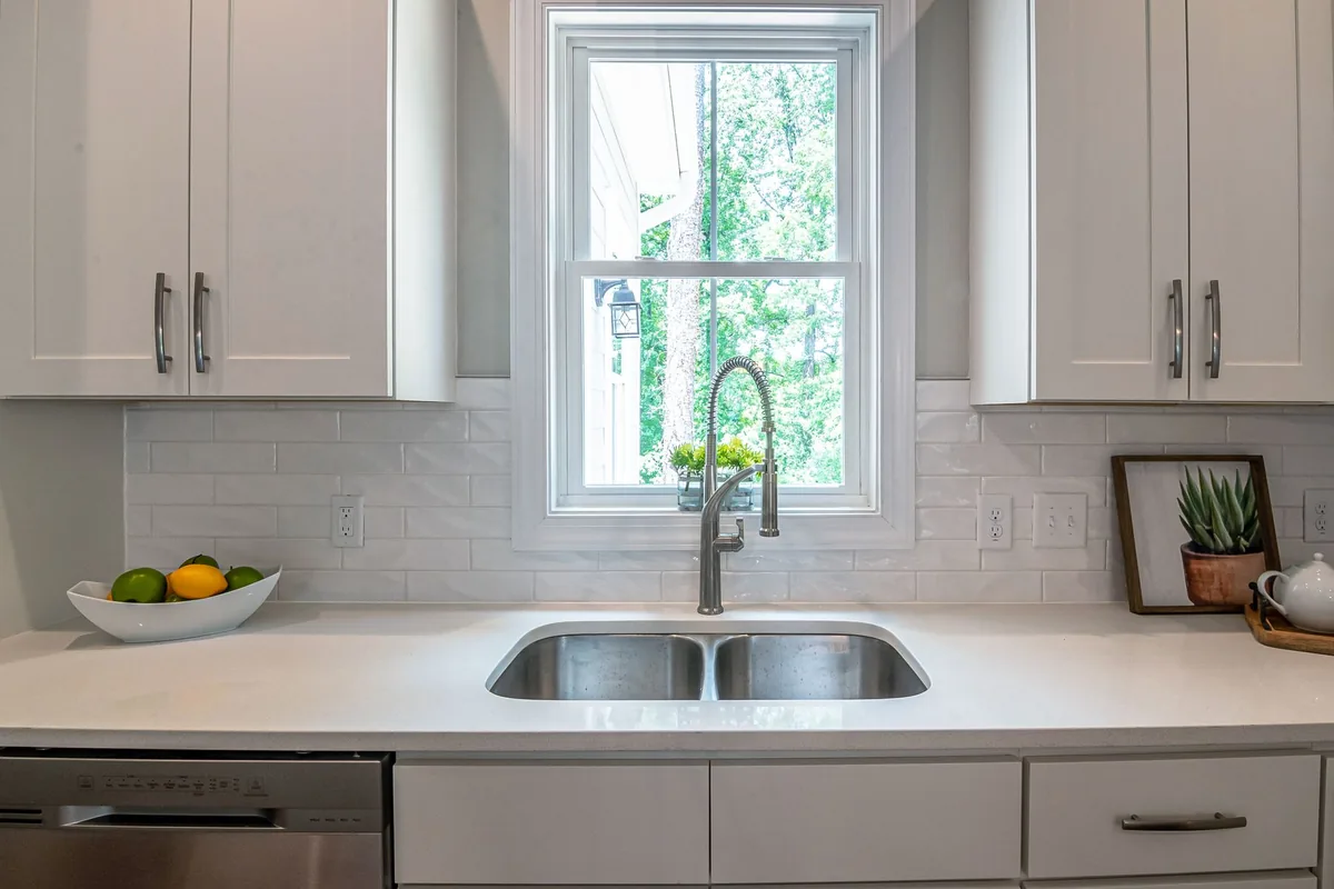 A double stainless sink in a bright white kitchen