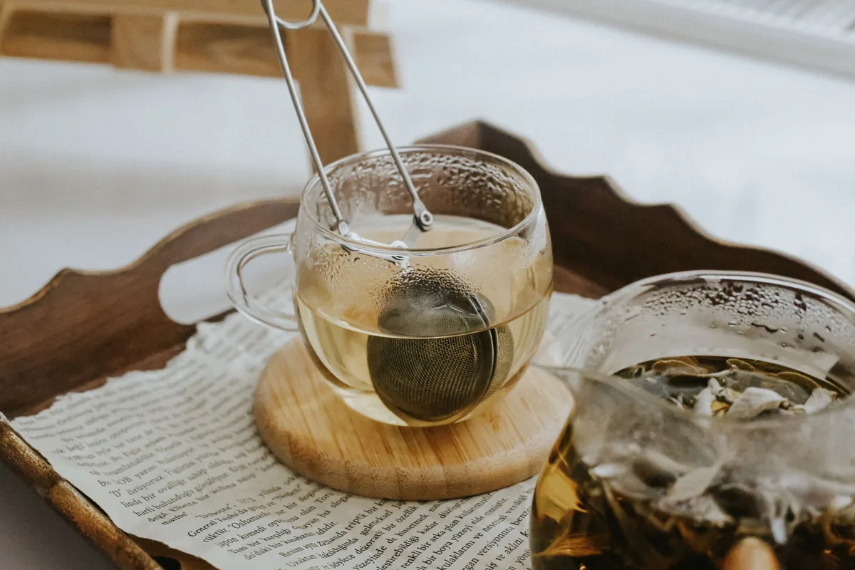 A glass cup of tea with a mesh tea strainer