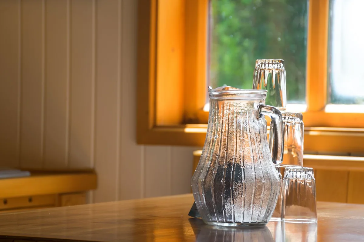A glass jug of water on a kitchen worktop by a window