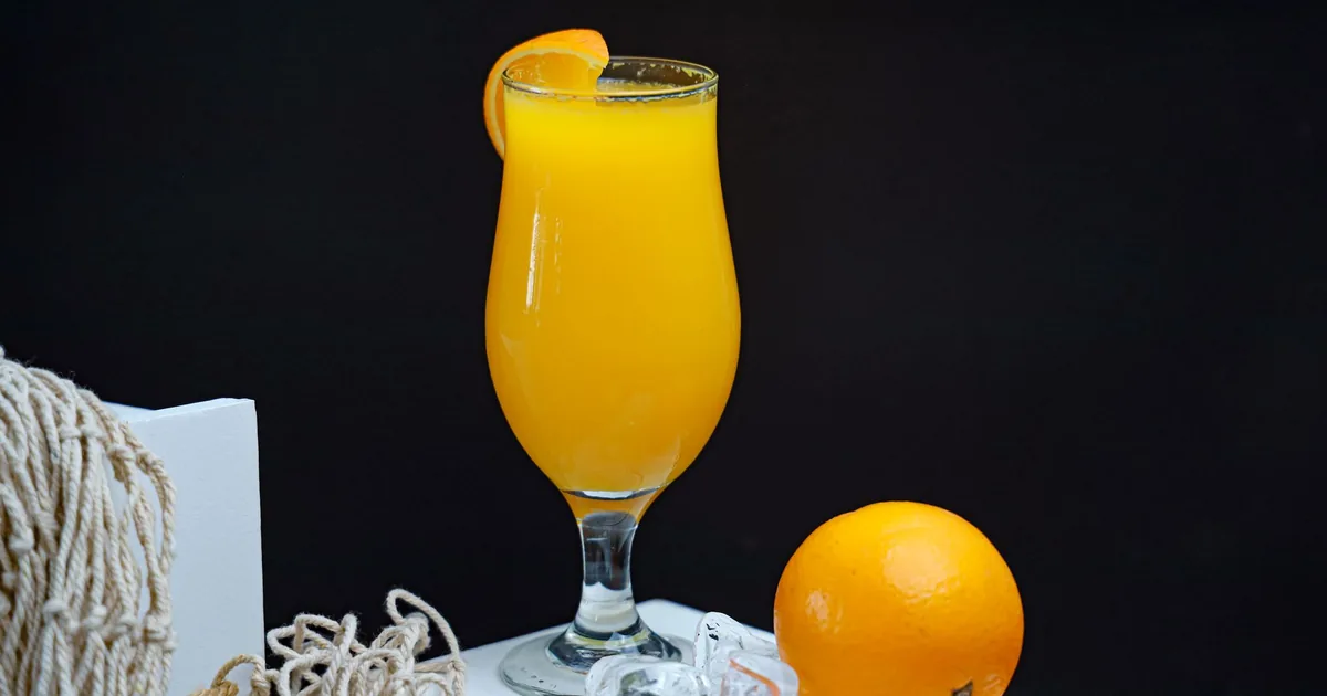 A glass of orange juice beside a whole orange