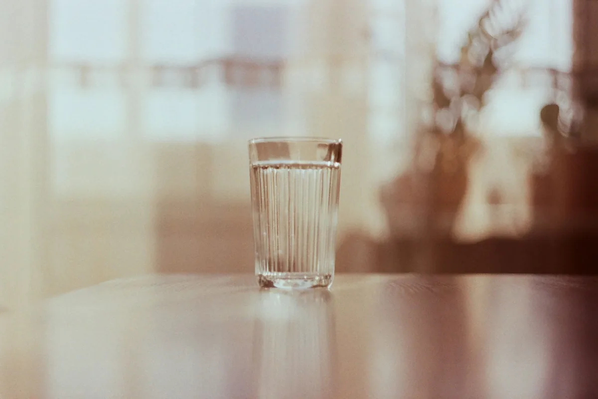 A glass of water on a table in warm window light