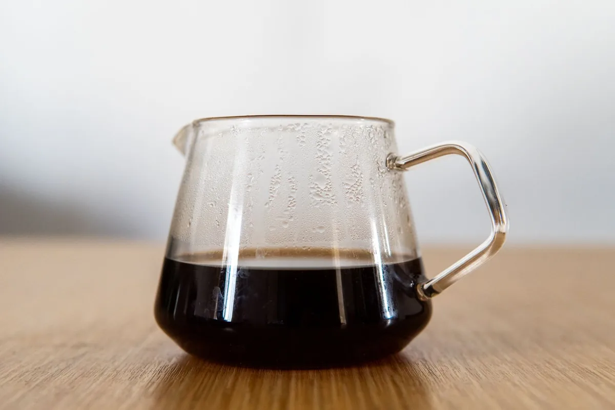 A glass server of black coffee on a wooden table