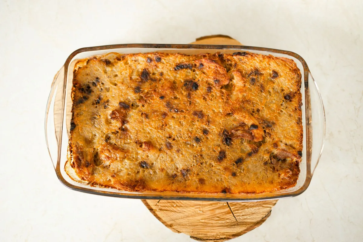 A golden baked casserole in a pan set on a cooling rack in a bright kitchen
