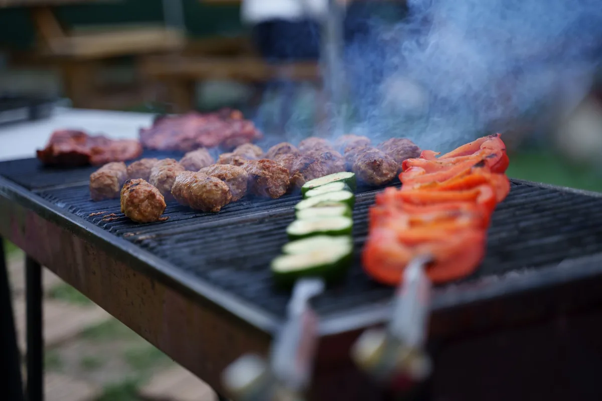 Meatballs, courgettes and tomatoes cooking on an outdoor grill