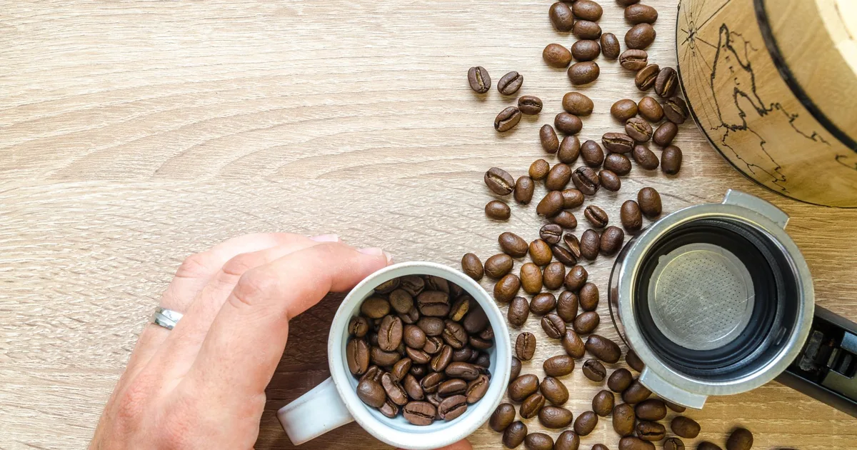 Coffee beans in a portafilter basket on a wooden table