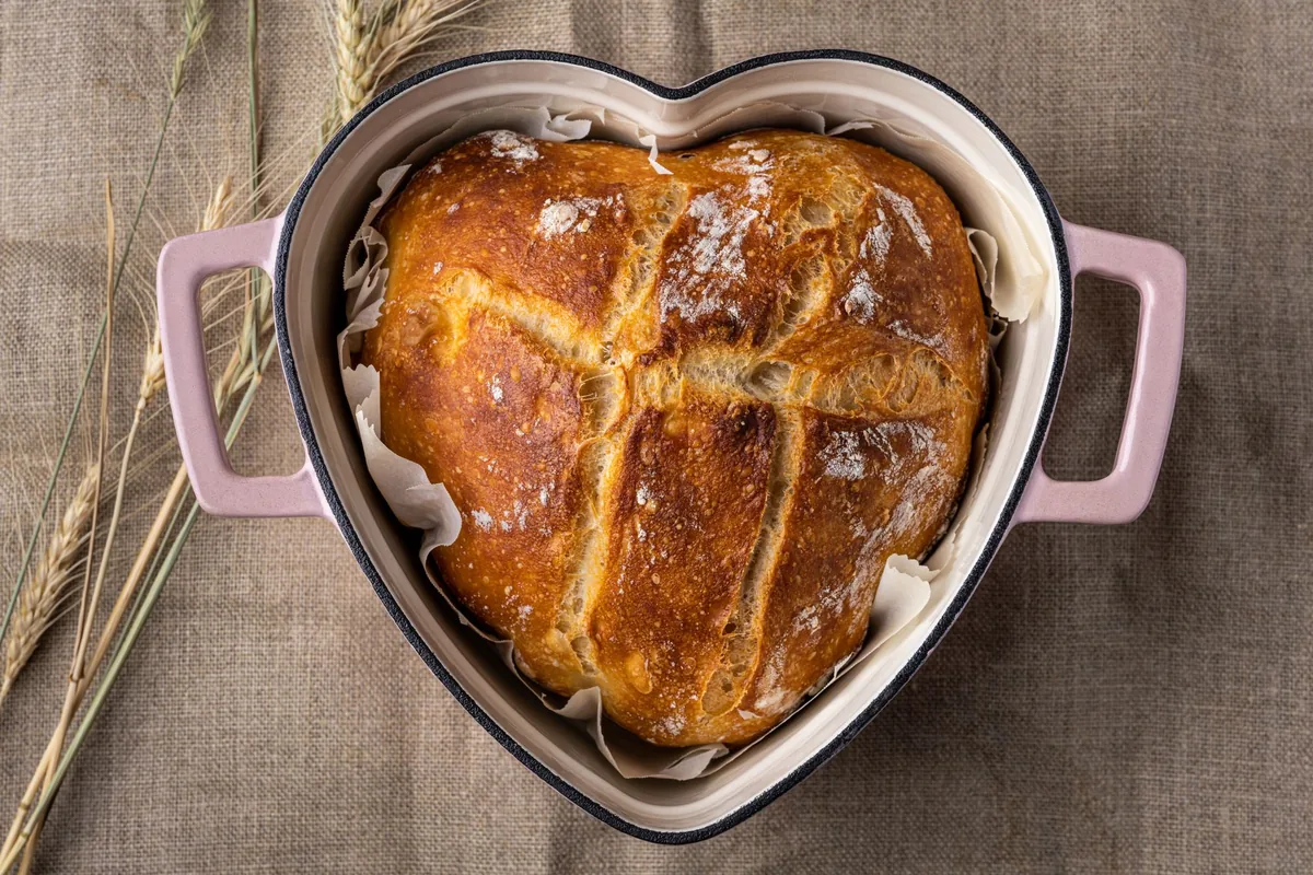 A heart-shaped enameled pot holding a baked loaf