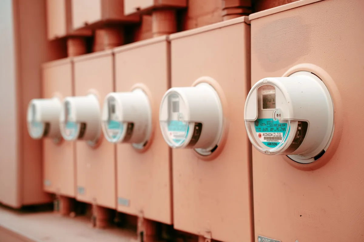 A household electricity meter mounted on a light wall, its display showing a reading