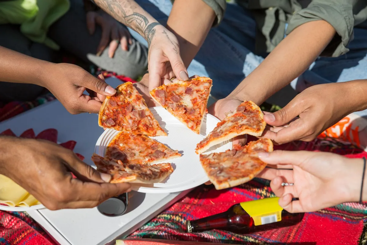 A large New York-style pizza slice on a paper plate