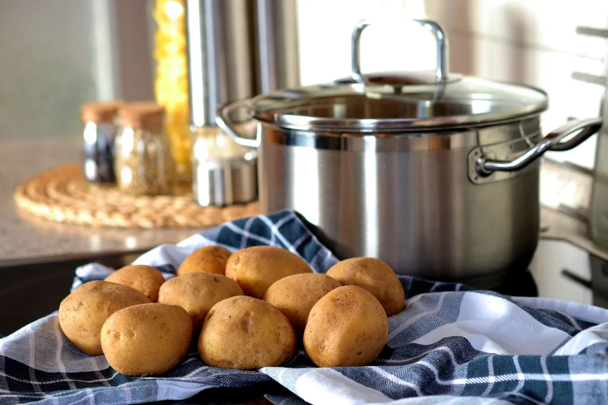 A lidded stainless pot beside a basket of potatoes