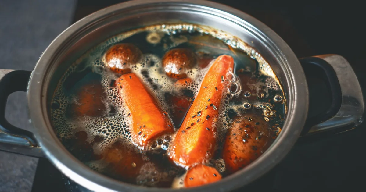 Carrots and potatoes boiling in a steel pot
